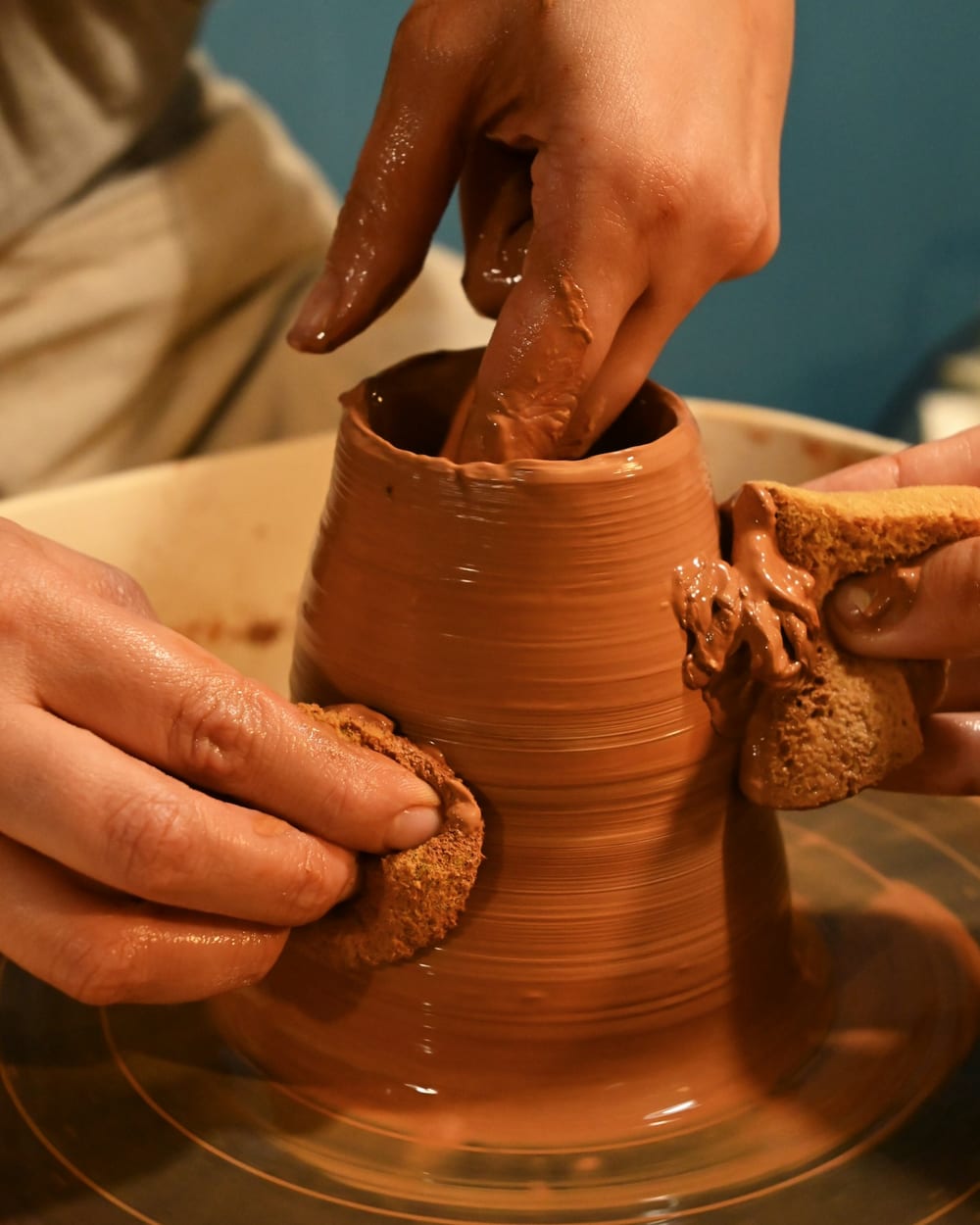 Potter's hands shaping a piece on the wheel