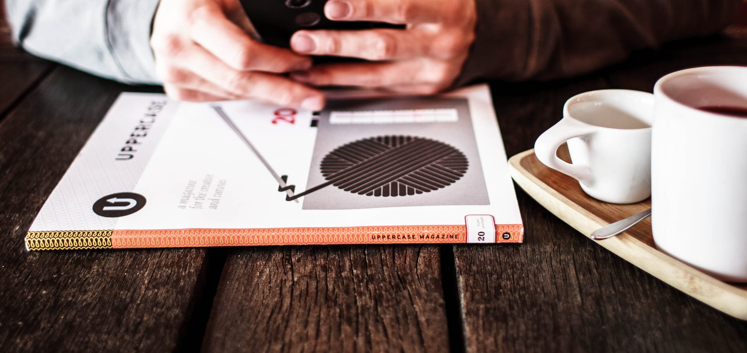 Persona escribiendo en su celular junto a un café