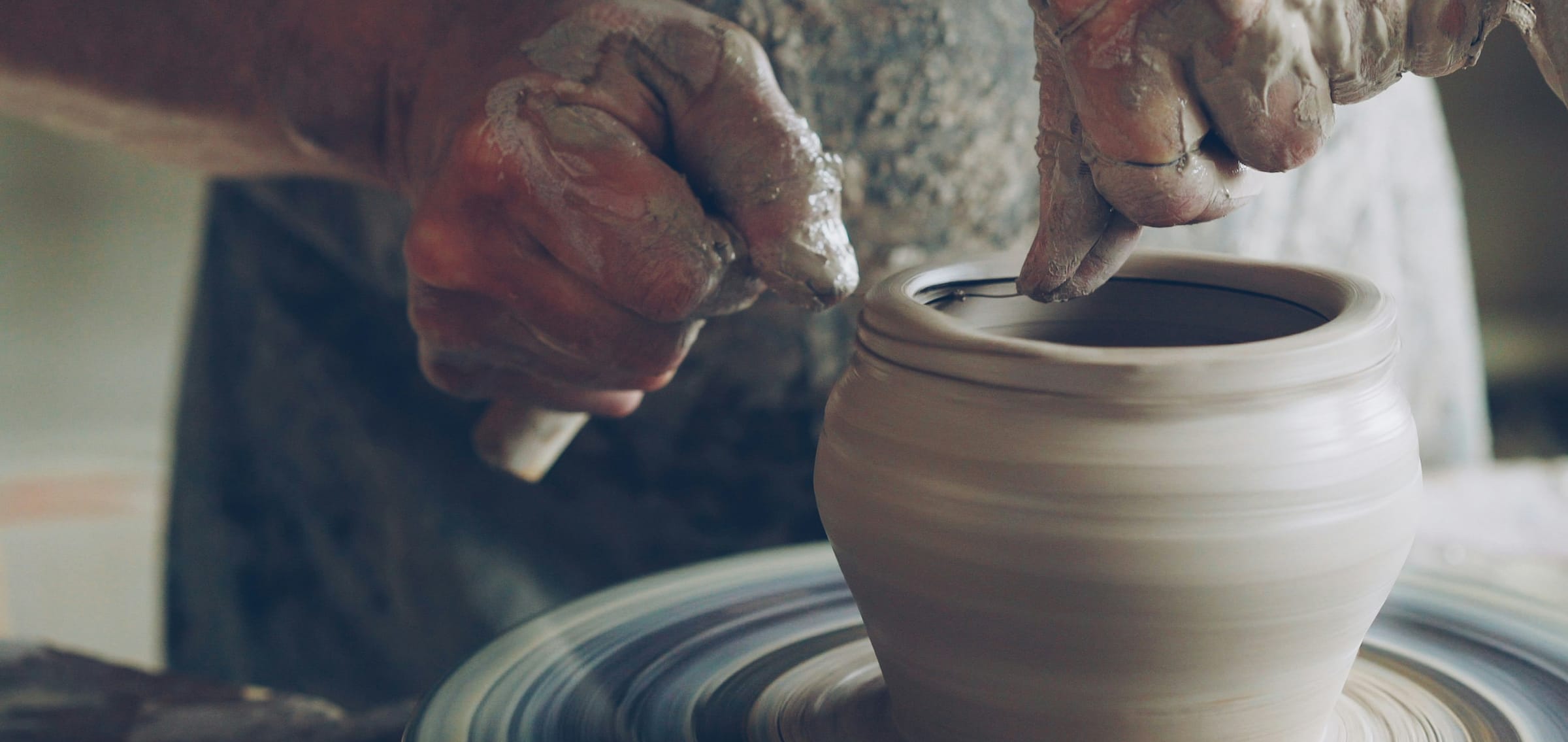 Potter's hands shaping clay on the wheel